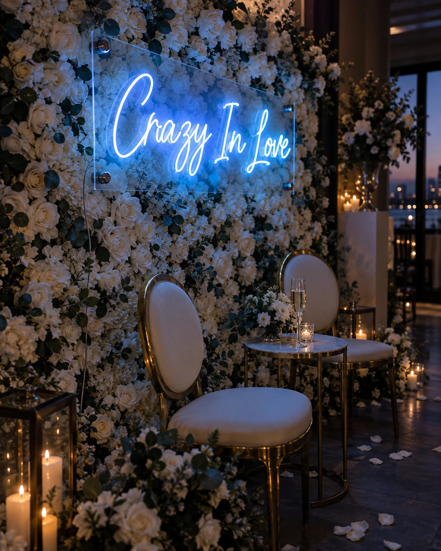 Crazy In Love blue LED neon sign mounted on a white flower wall at a wedding