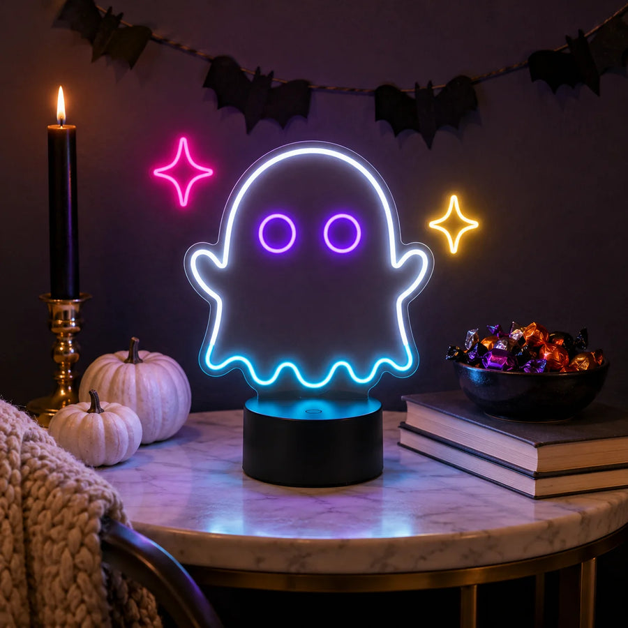 Ghost neon desk light glowing on a Halloween table beside pumpkins and candy