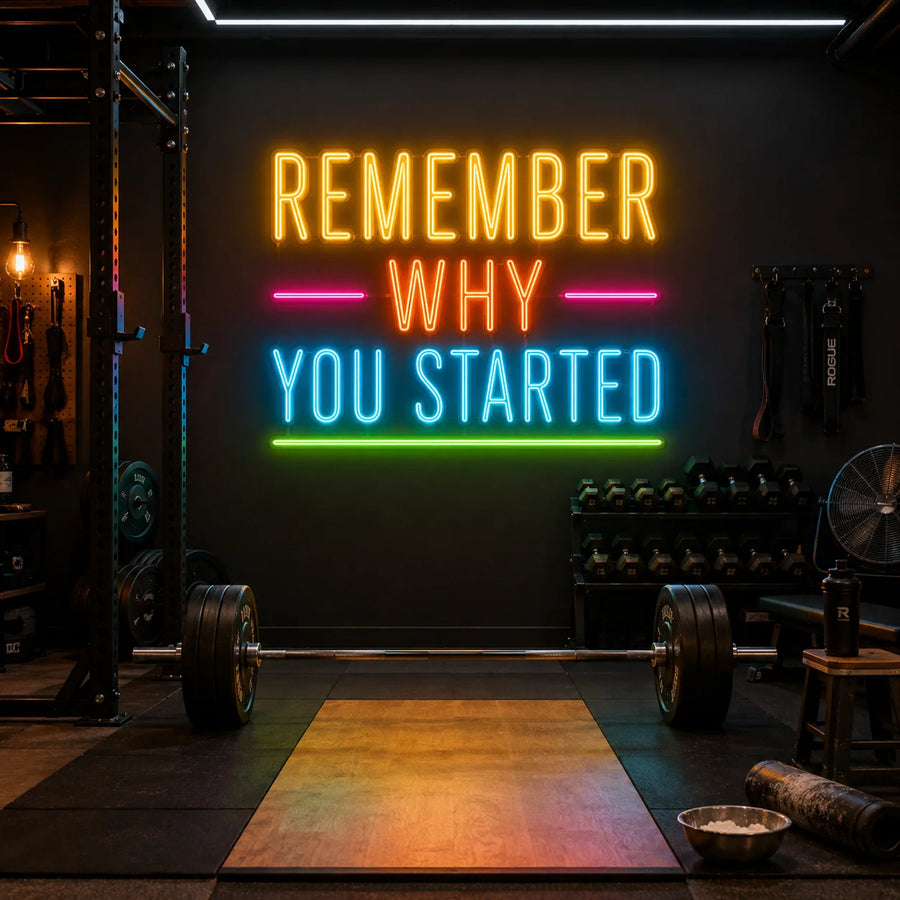Remember Why You Started neon sign glowing above a lifting platform in a home gym