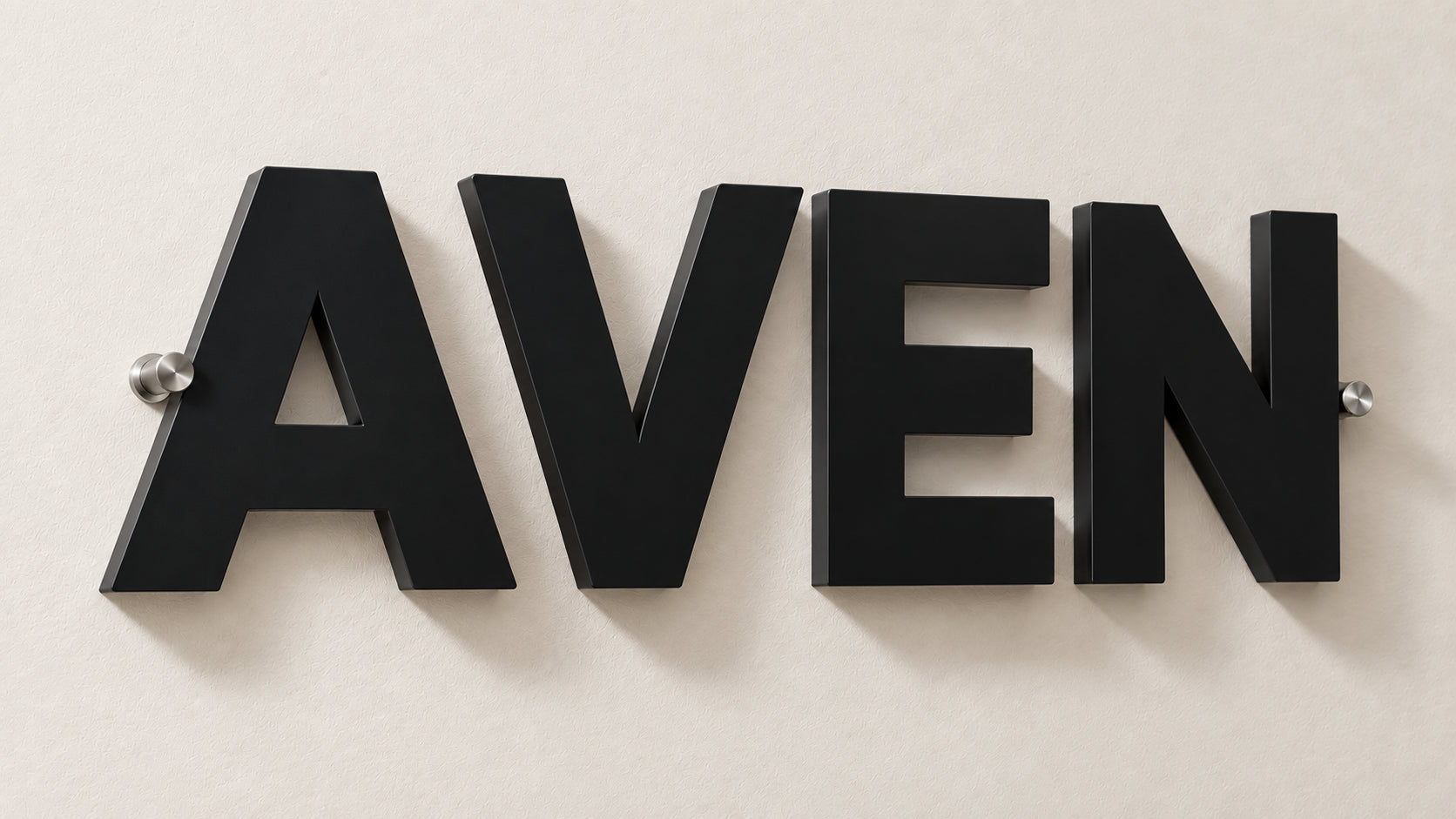 Non-illuminated dimensional matte black acrylic sign spelling AVEN on chrome standoffs casting a shadow on a pale wall