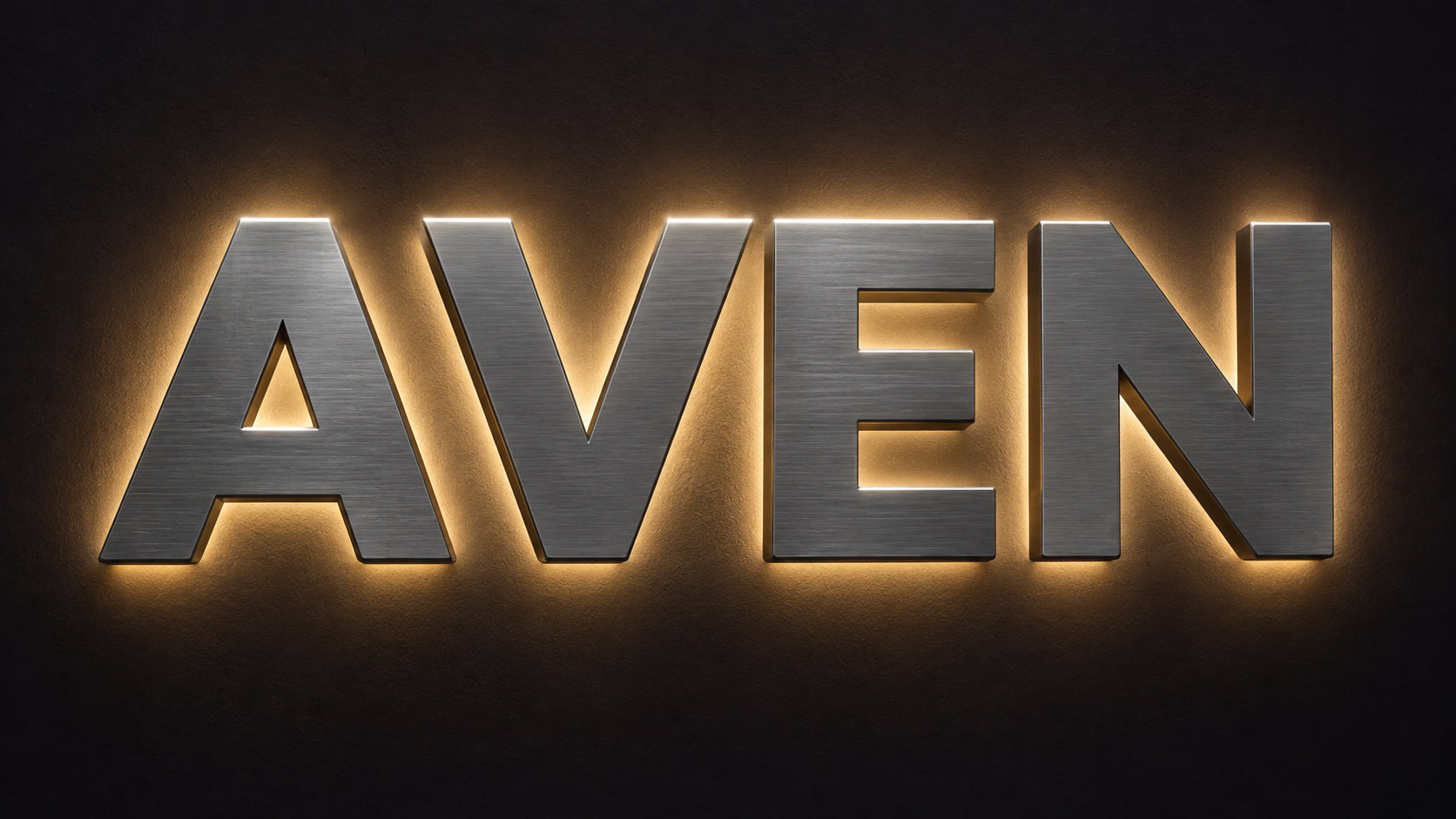 Halo-lit reverse channel letter sign spelling AVEN with solid brushed metal faces and a warm backlight glow on the wall